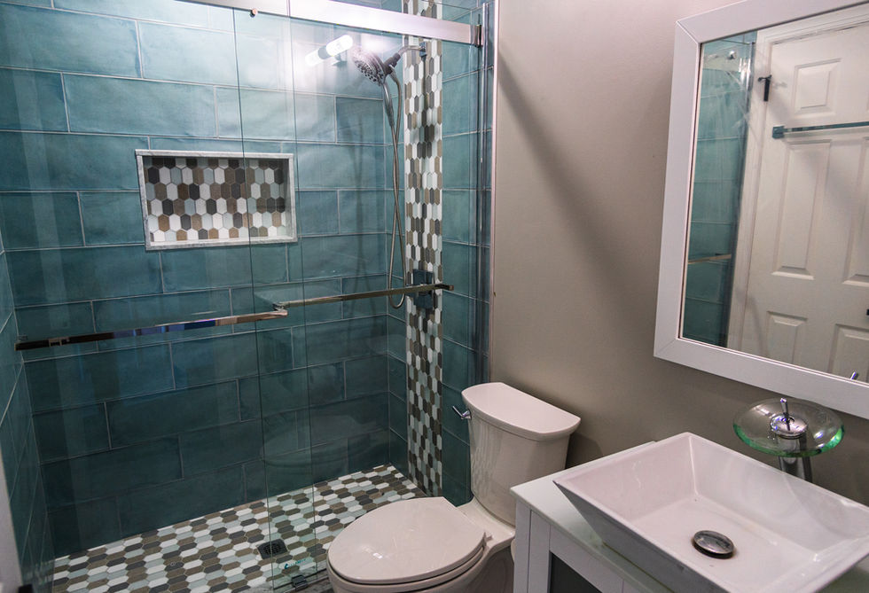Bathroom with a shower that has glass doors and blue wall tiling