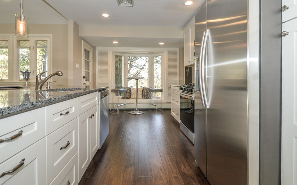 Stainless steel fridge next to a large open countertop area, with cafe table and chairs in the background