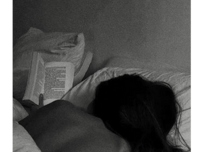 black and white photograph of a woman reading in bed