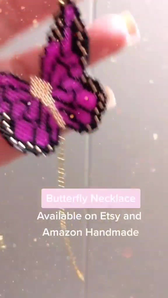 Thumbnail: a hand holding and swinging a butterfly necklace