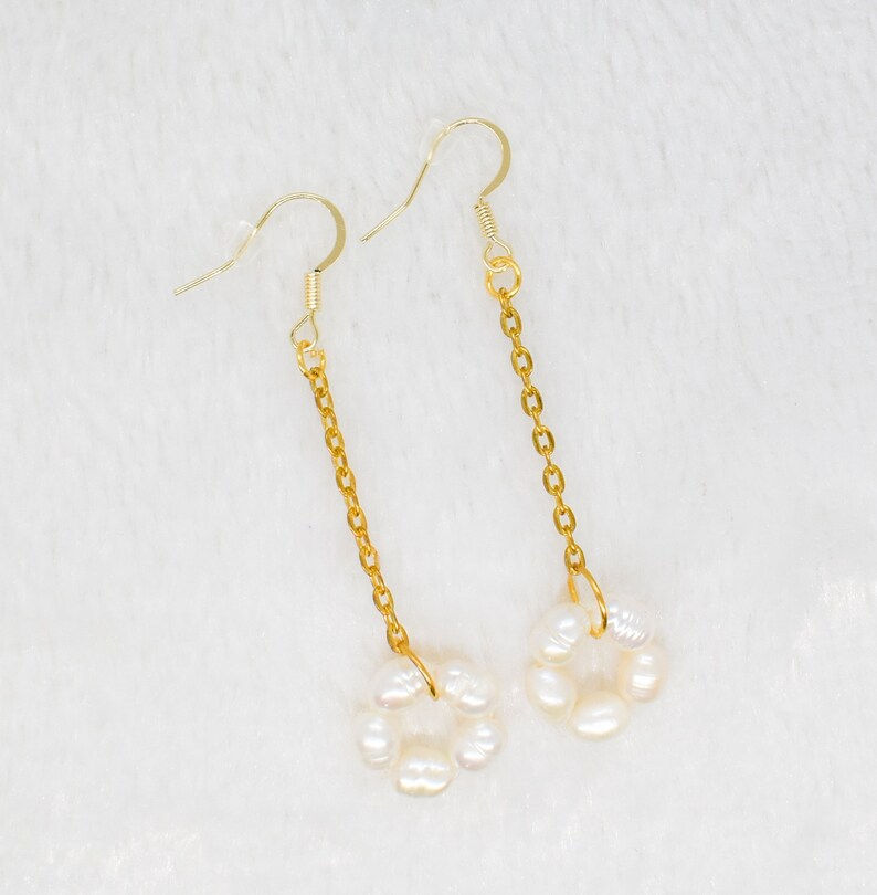 earrings made with 14k ear wires. fresh water pearls on a circle and hanging on a gold plated chain showcased on a white pillow