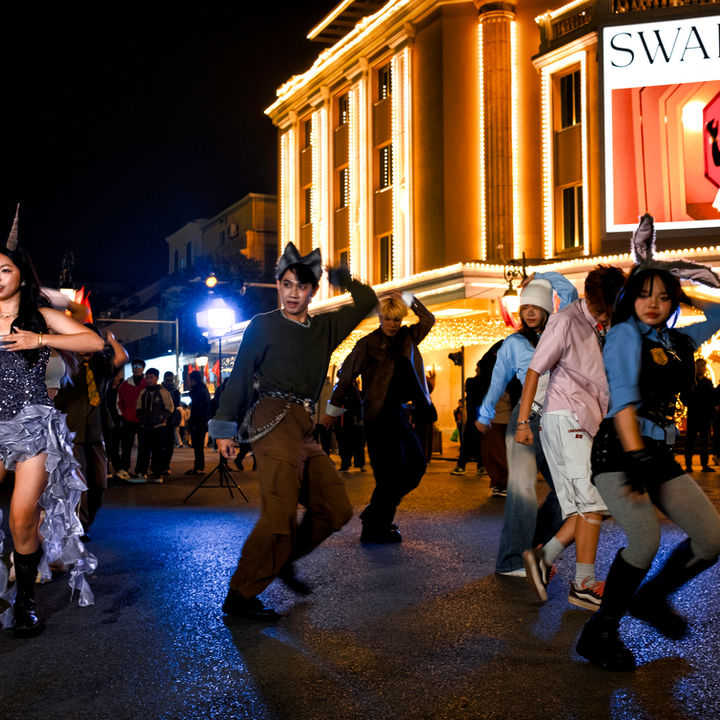 Own the Street — University students performing choreographed dance on closed Tràng Tiền street, festival lights and Swarovski billboard behind