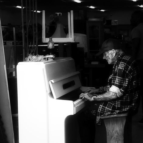 Heavily tattooed man playing a piano