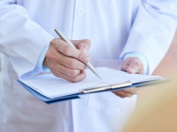 Gros plan d'un médecin de sexe masculin en blouse de laboratoire remplissant un formulaire médicaGros plan d'un médecin de sexe masculin en blouse de laboratoire remplissant un formulaire médical