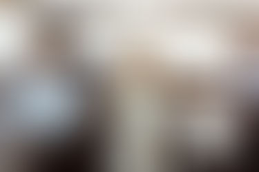 Un couple élégant trinquant avec des coupes de champagne sur un balcon avec une vue discrète sur le port de Monaco illuminé, loin de l'agitation de la course