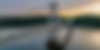 A suspension bridge spanning the Hudson River, with forested hills and calm water in the background.