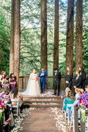 Bride and groom at outdoor wedding ceremony in the redwoods with flower petal aisle at amphitheater of the redwoods at pema osel ling