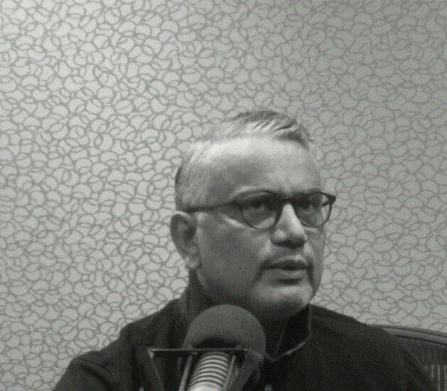 A headshot of Taoufik Ben Ammar in front of a microphone.