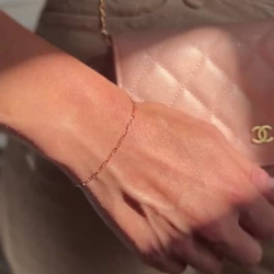 woman wearing a gold filled bracelet holding a pink purse