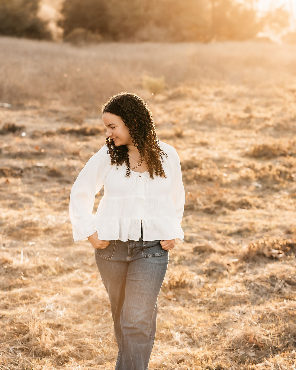 high school senior young lady getting her photos taken in golden sunlight in a field
