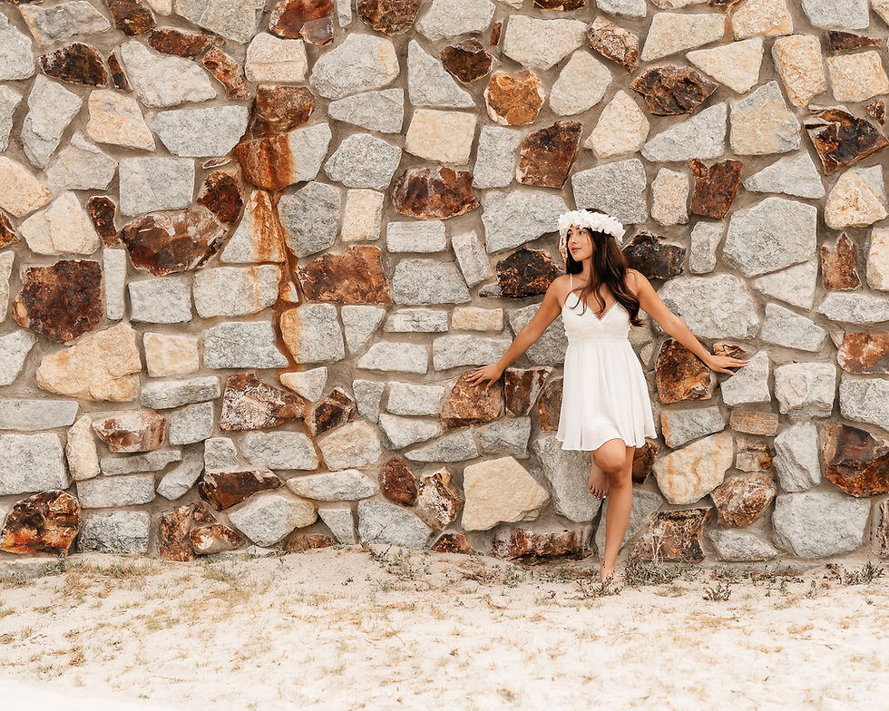A high school senior girl on the beach taking graduation photos