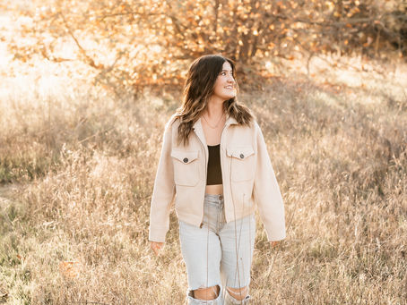 senior photos in a field at sunset