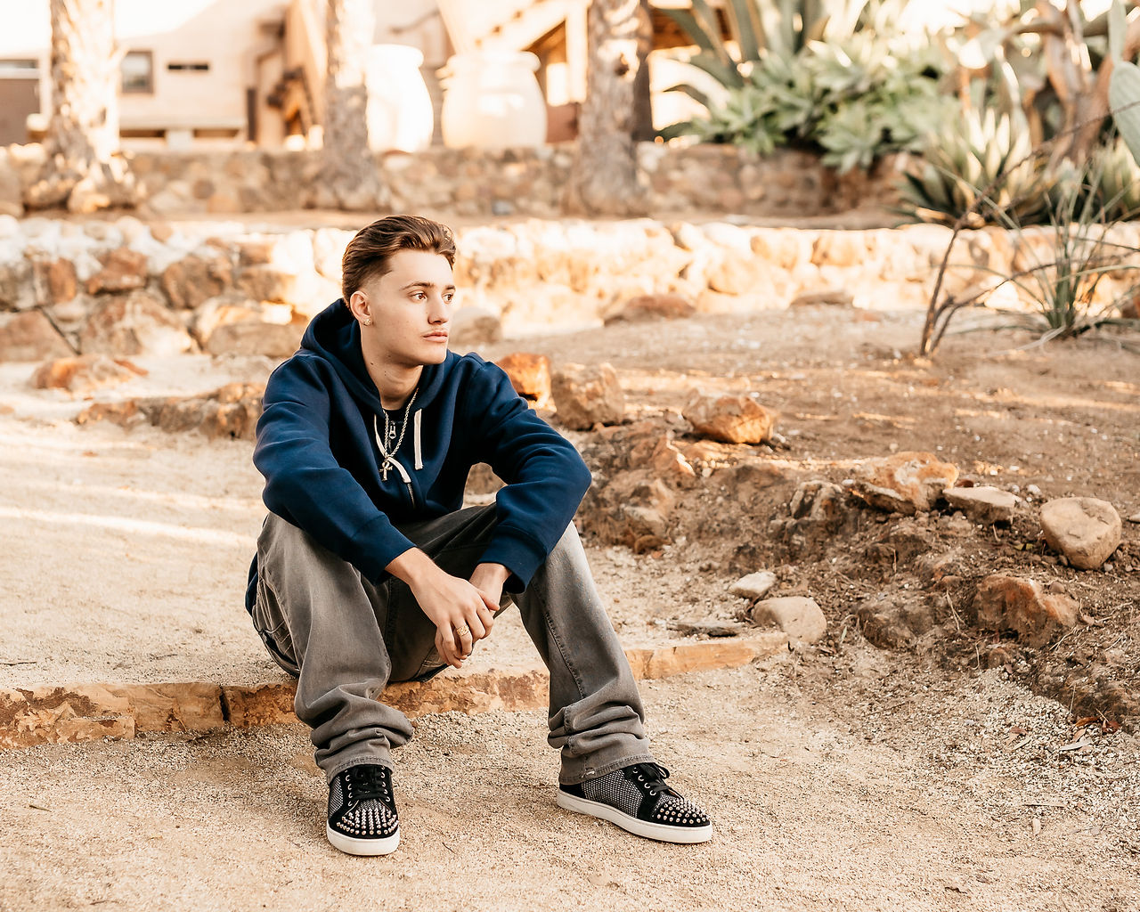 High school senior portrait of a young man in Balboa Park, captured by a senior photographer. He poses confidently with natural light highlighting his features, surrounded by the park’s iconic architecture and lush greenery. #SeniorPortraits