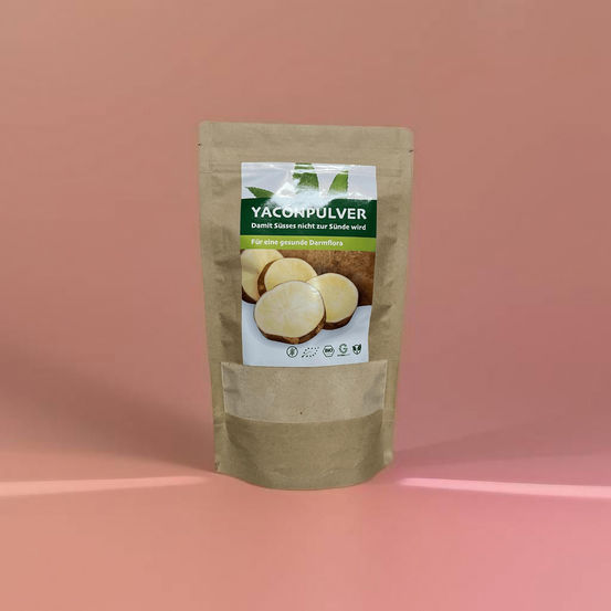 Yacon-Pulver in der Produktverpackung auf rosafarbenem Hintergrund
