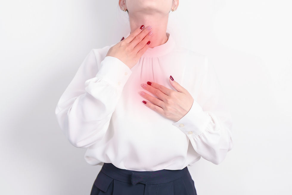 This image shows a woman suffering from GERD. The woman has fancy red and white dotted nails. She holds her heart and her throat. Those areas are highlighted in red against her white shirt.