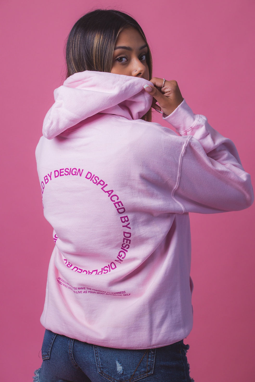 A Woman Wearing a Pink hoodie while showing its design as a representation of Print On Demand