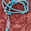 Thumbnail: Turquoise beaded necklace with a feather pendant, resting on a brown surface.