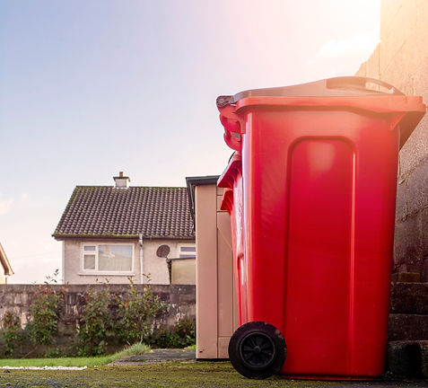 Red small wheelie recycling plastic bins in a back yard of a house. Waste disposal industr