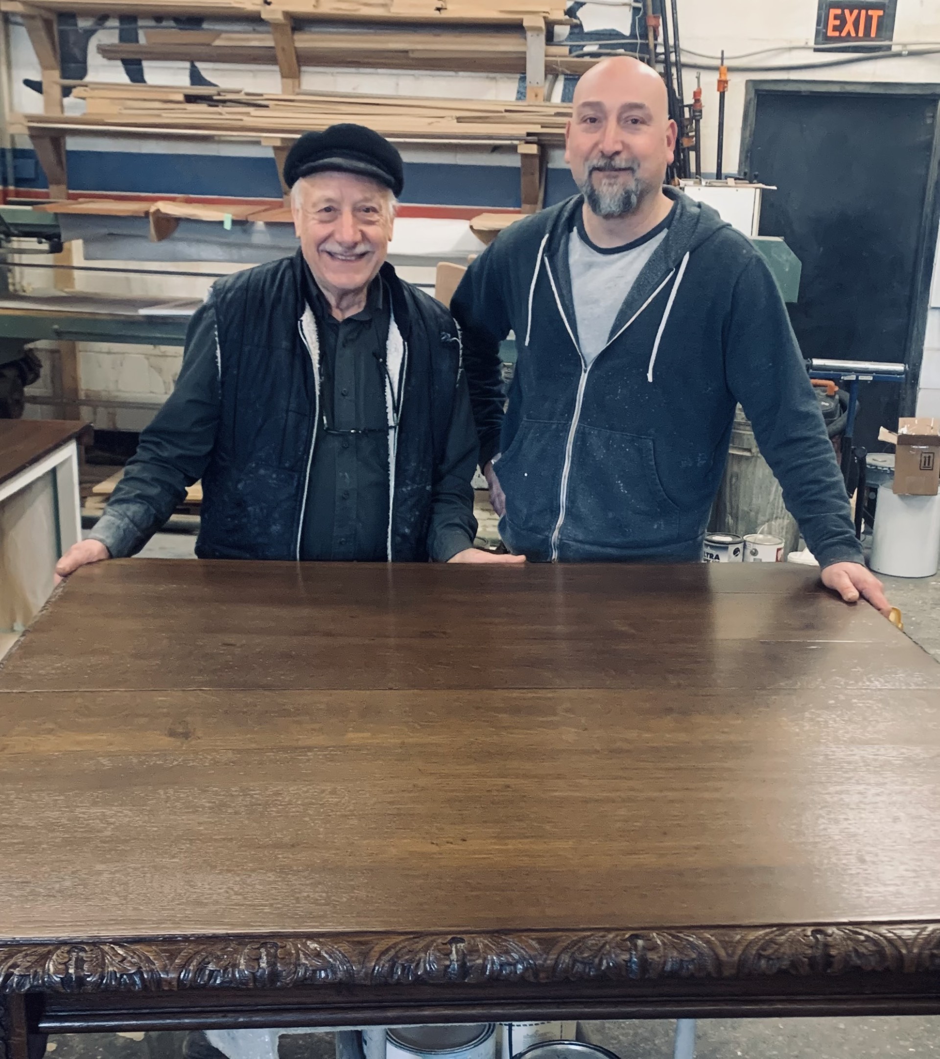 Pasquale and Carlo together in the workshop behind a restored carved wooden table