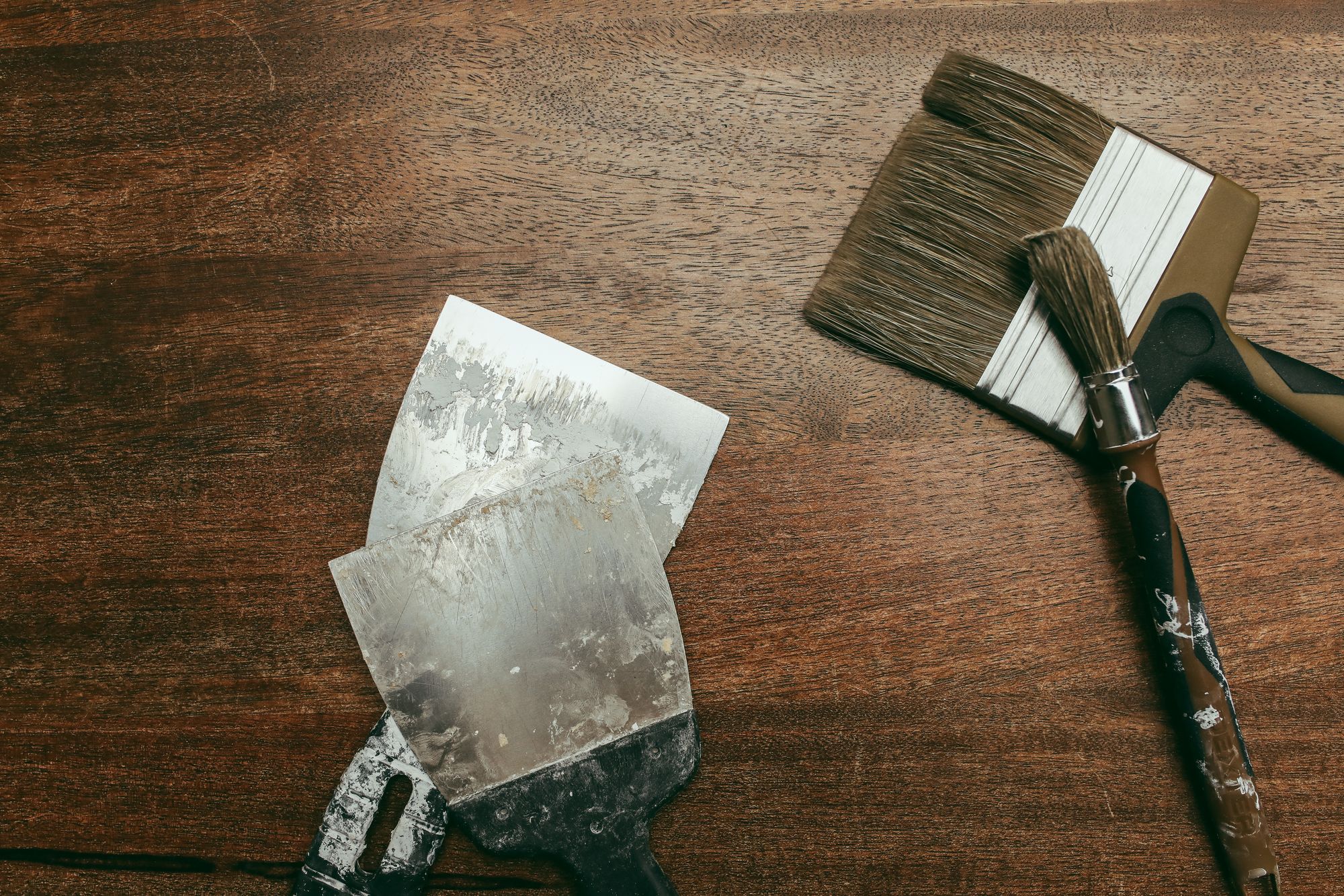 Refinishing brushes and scrapers arranged on a wooden work surface
