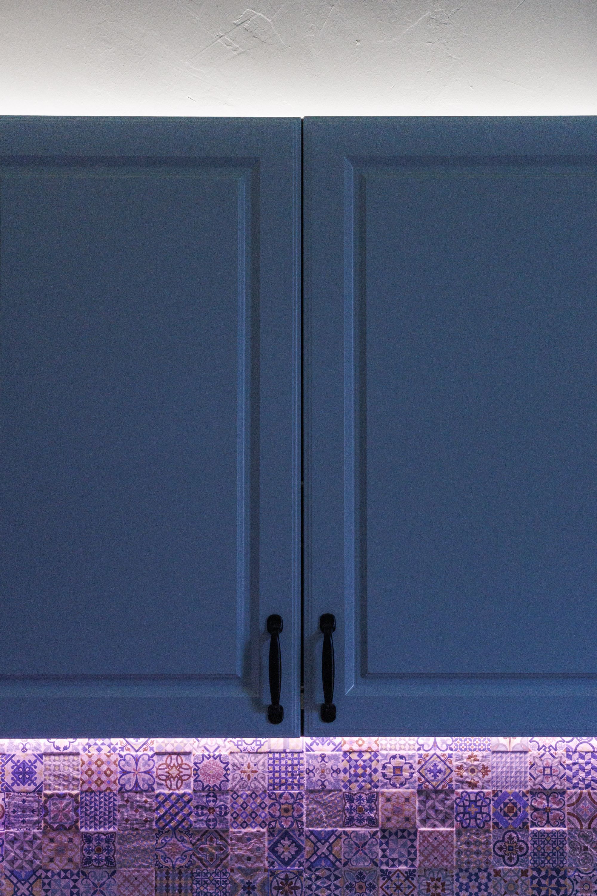 Blue kitchen cabinet doors above a patterned tile backsplash