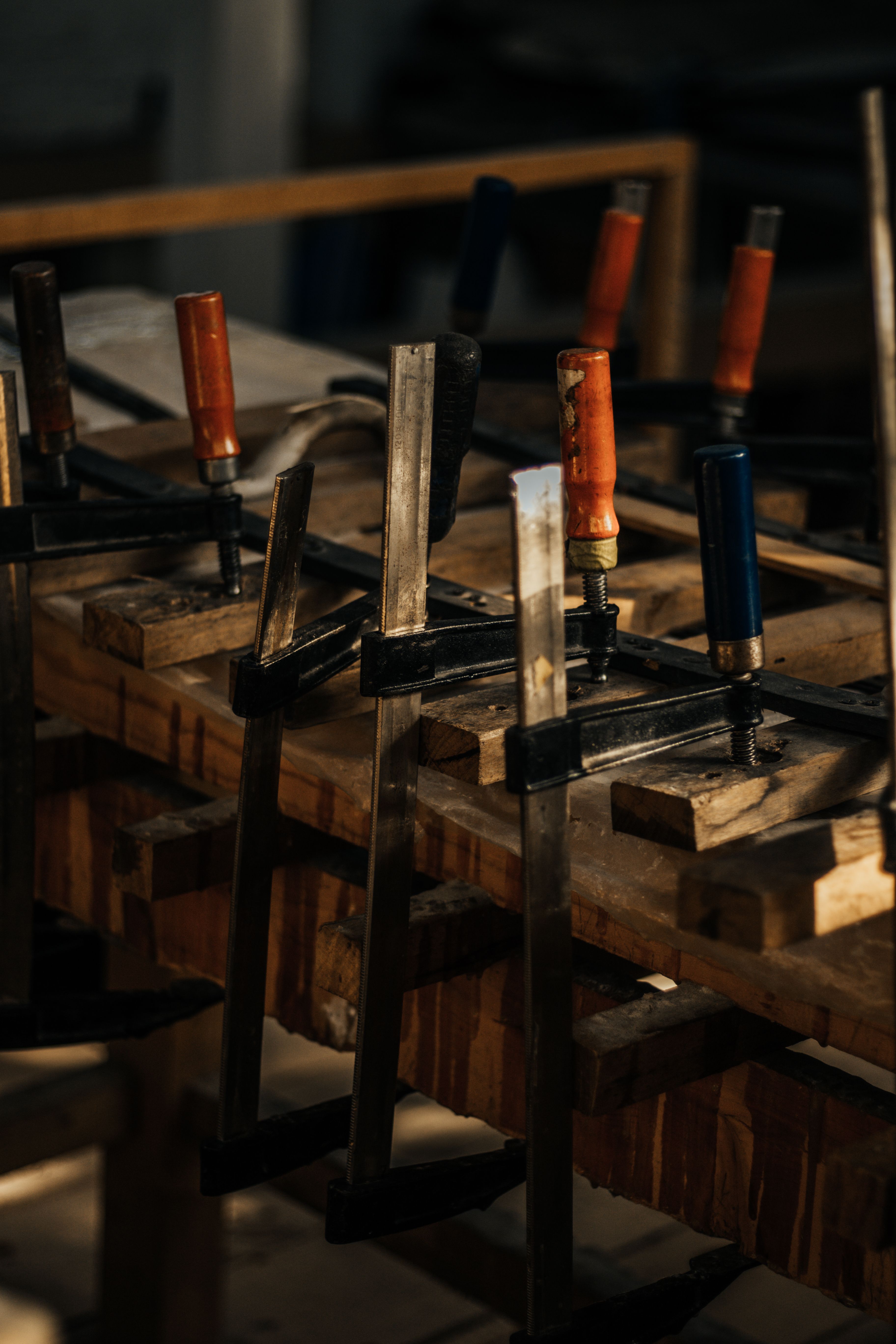 Wooden furniture parts clamped together for repair on a workshop bench