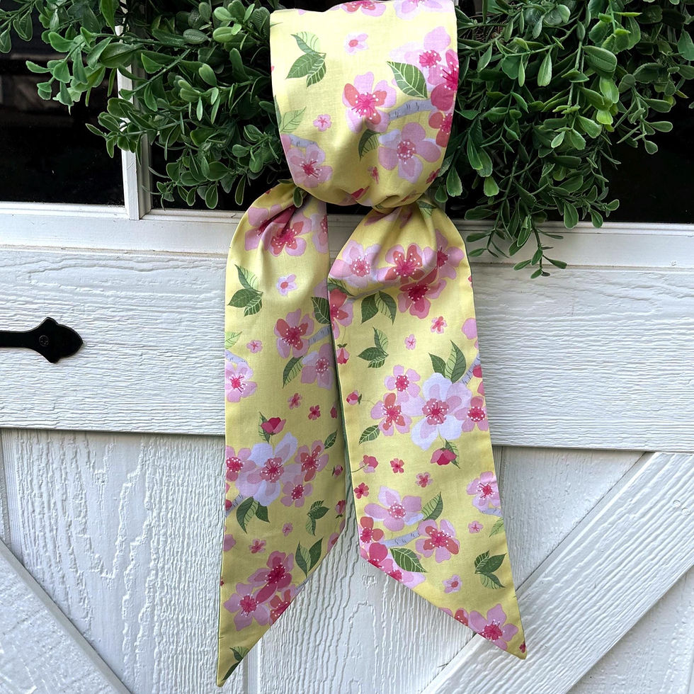 Thumbnail: A handcrafted reversible wreath sash featuring a vibrant yellow floral pattern with pink and green accents, in a simple knot