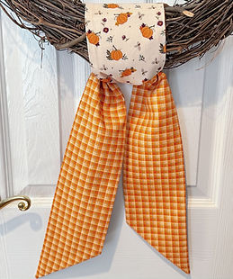 Orange and Cream Pumpkin reversible fabric seasonal knot wreath sash tied to a grapevine wreath