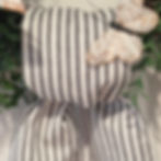 Black ticking stripe cotton wreath sash draped over a green boxwood wreath, tied in a simple knot with long tails on a neutra