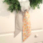 Thumbnail: blue gingham check with yellow and pink daisy wreath sash tied on a sage green front door of a spring home