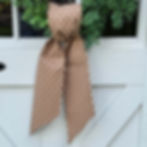 Brown floral Simple Knot wreath sash tied on a boxwood wreath, styled on a white barn door for rustic fall entryway décor.