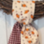 pumpkins and burgundy simple knot wreath sash styled on a grapevine wreath for autumn harvest outdoor decor