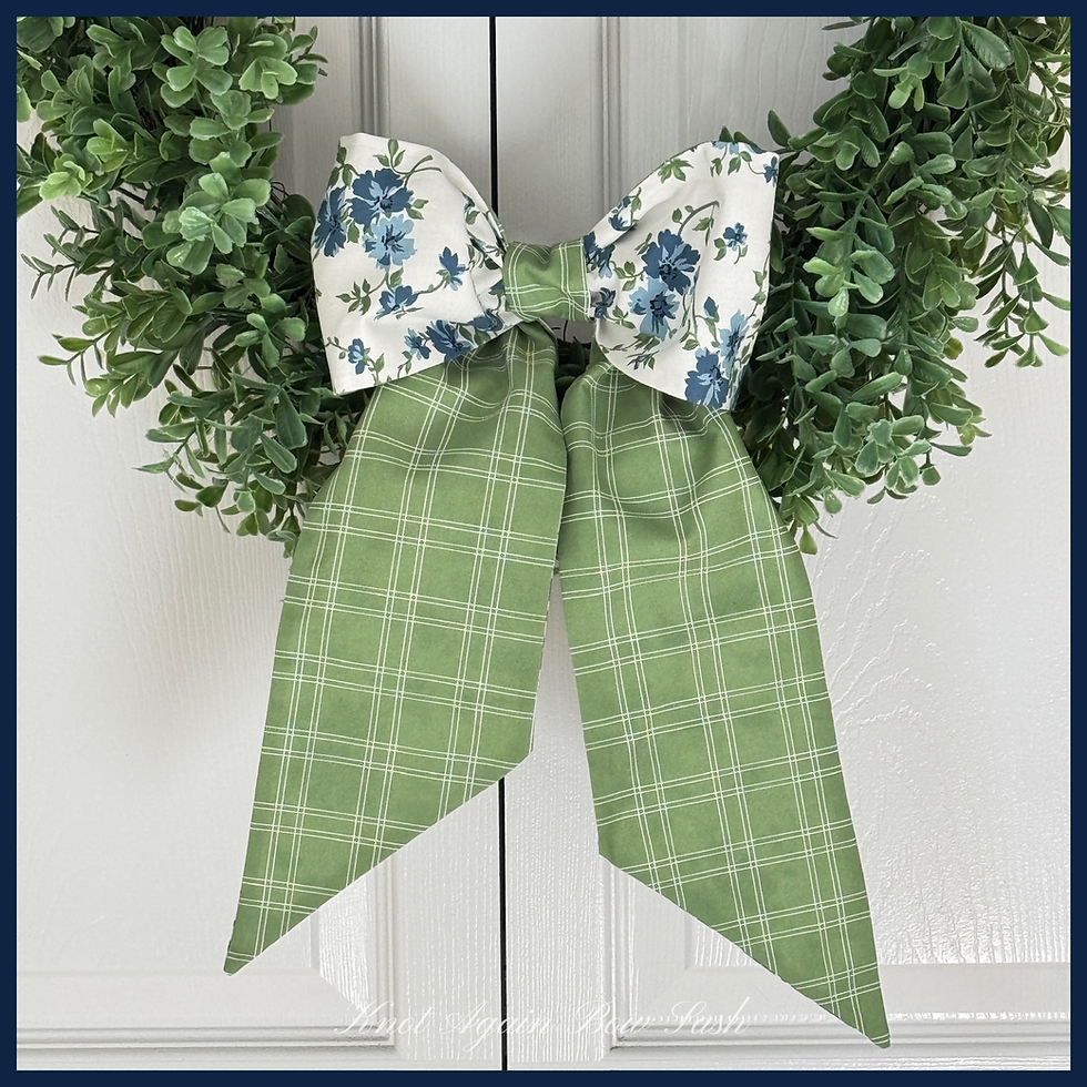 The French Twist bow styled on a wreath, featuring blue floral loops and green leafy tails for a classic front door look.