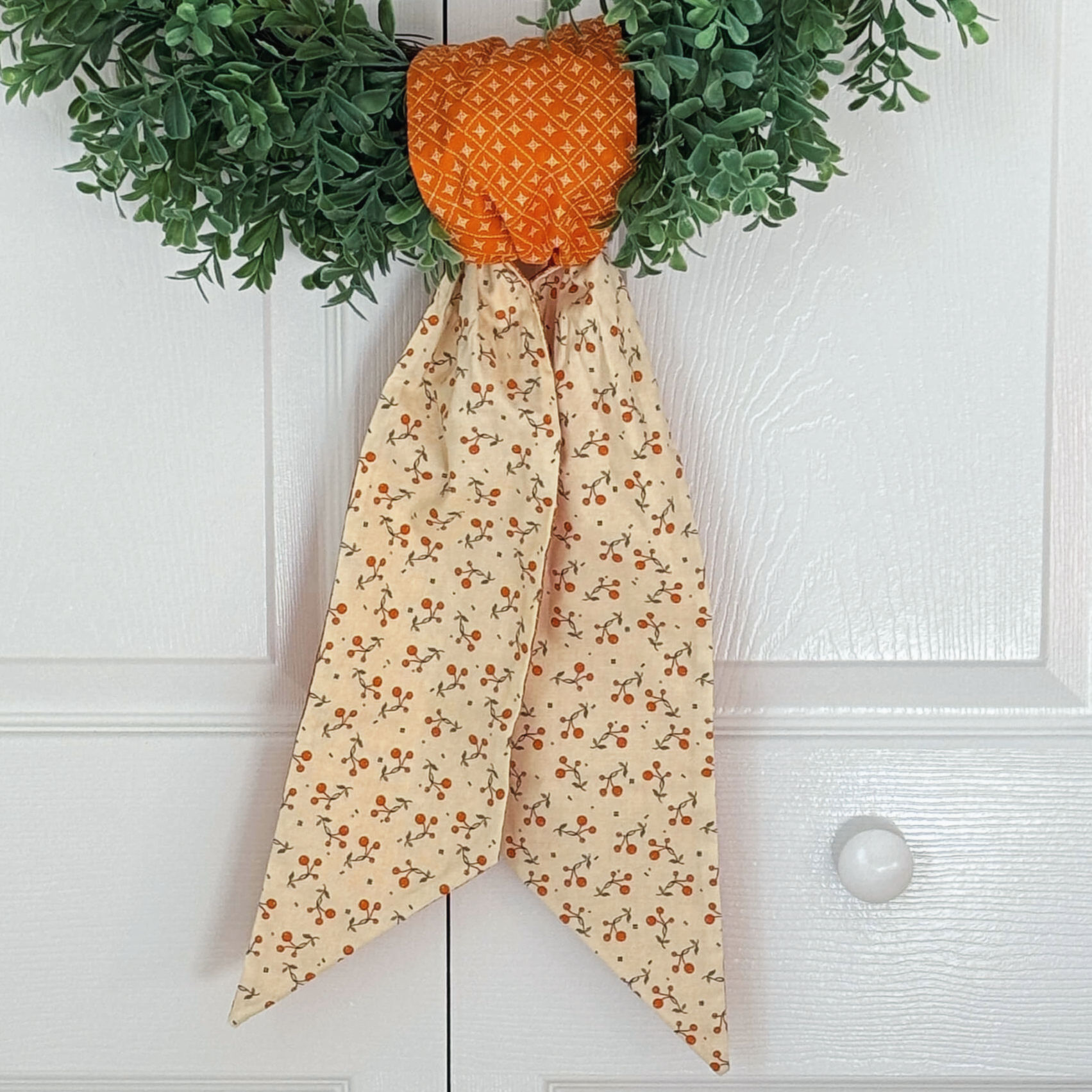 Orange and cream berry vine fall wreath sash tied on boxwood wreath, autumn front door decor