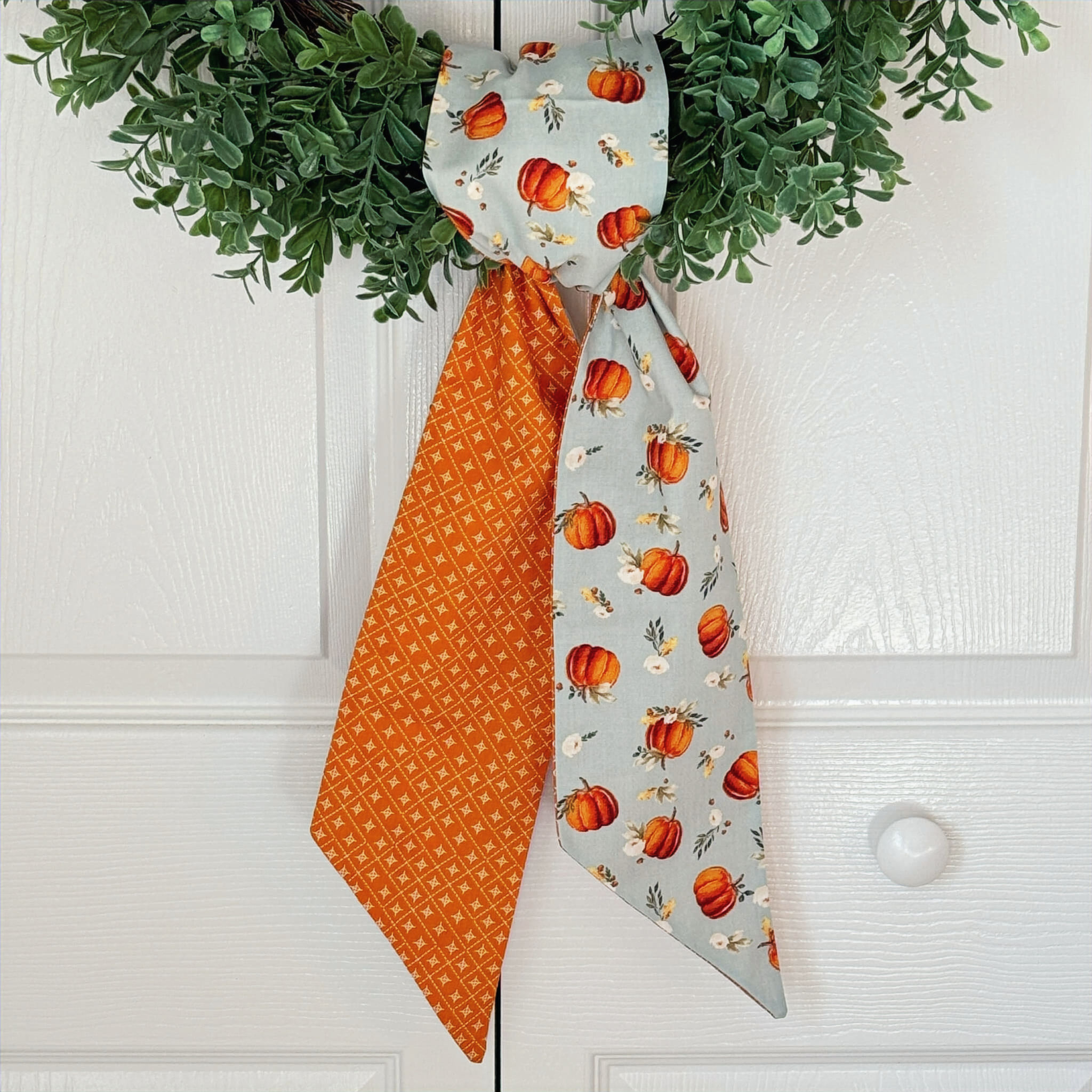 Pumpkin and blue floral reversible wreath sash tied on boxwood wreath, fall front door decor