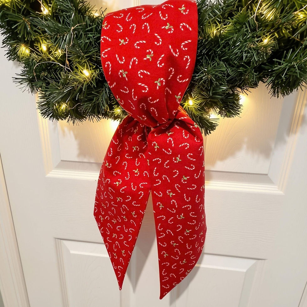 Red candy cane wreath sash displayed on evergreen wreath with warm white lights against white door