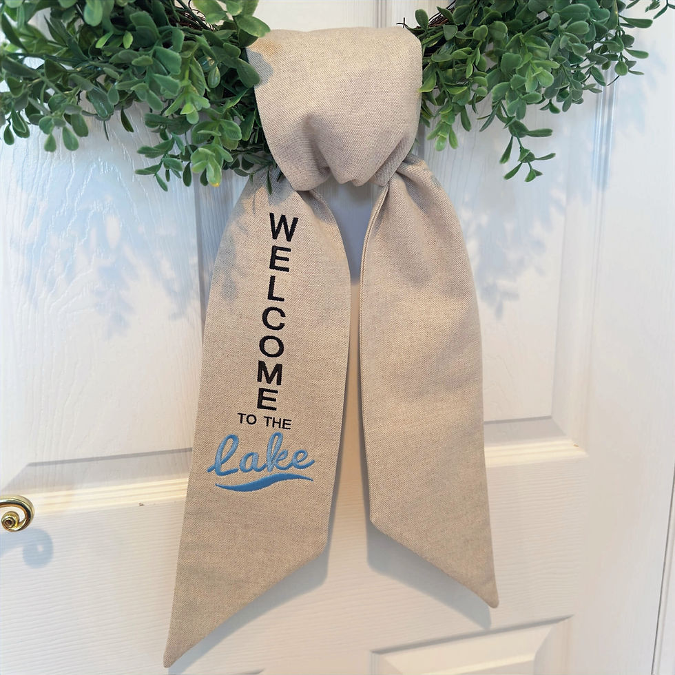 Thumbnail: Neutral linen wreath sash tied in a simple knot on a green wreath, embroidered “Welcome to the Lake” for lake house door deco