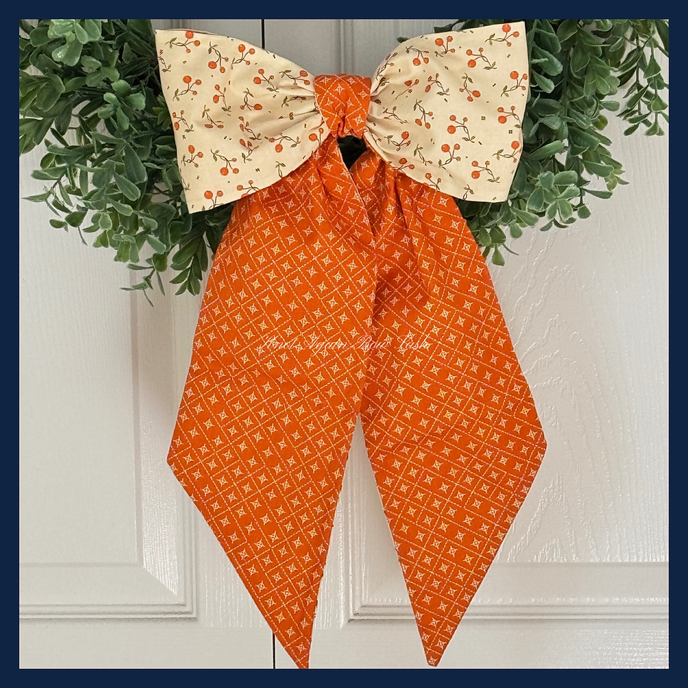 The Harvest Berry sash styled in a full bow on a wreath, showing ivory berry fabric loops and orange diamond tails.