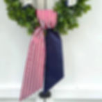 red white and blue patriotic reversible wreath sash tied in a simple knot on a green boxwood wreath on a white door