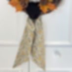 Cream and black marigold floral wreath sash tied on pinecone wreath, fall front door decor