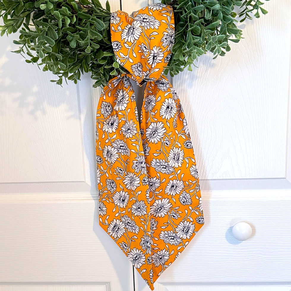 Thumbnail: Reversible wreath sash in navy floral fabric with yellow reverse tied simply at the base of a wreath.
