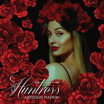 Image of Ashleigh Watson wearing red rose crown looking over her shoulder seductively into camera. Blonde hair and sultry makeup with red lips. Red roses scattered across foreground.