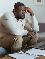 Black man pondering in front of papers
