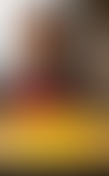 A man in a red apron smiles while cooking a large, steaming dosa on a stove. Open windows reveal misty mountains in the background.