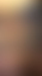 A glass of chai on a wooden table overlooks a river at sunset, surrounded by hills and distant lit buildings, creating a serene atmosphere.