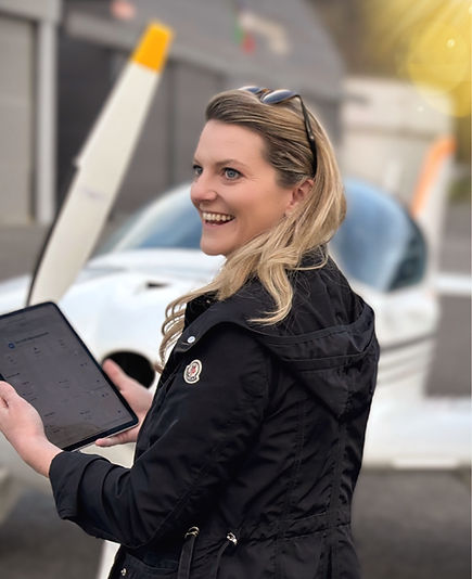 Smiling aircraft owner managing maintenance schedule with FlightGuard aviation app next to light aircraft