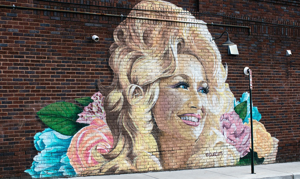 Muurschildering van Dolly Parton op een bakstenen muur langs het trottoir.