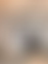 A woman looks down at a man, they are dressed in wedding attire. She is holding a big bouquet of flowers.