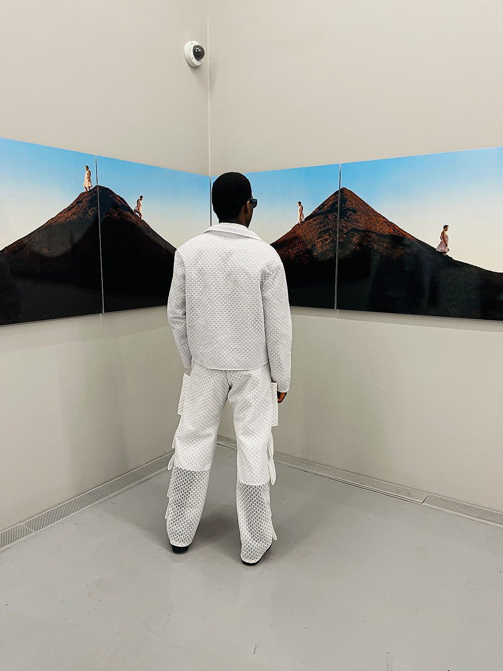 Thumbnail: Person looking at art, wearing white outfit and a Dangly Blazer in gallery setting.