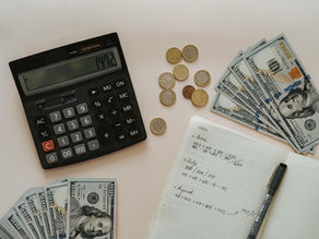 Calculator, notebook, and cash on a desk representing financial records and accrual accounting.